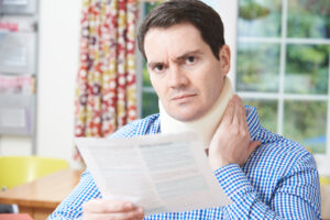 man reading letter after receiving neck injury