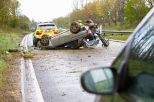 car lying upside down after a crash on a motorway with a police car beside it