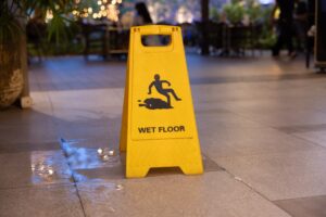 A yellow sign with a man falling on it and the words Wet Floor